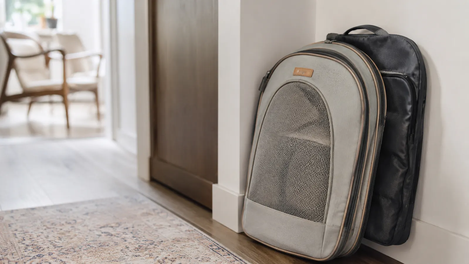 A soft-sided carrier collapsed and folded flat, tucked neatly against a wall in a hallway